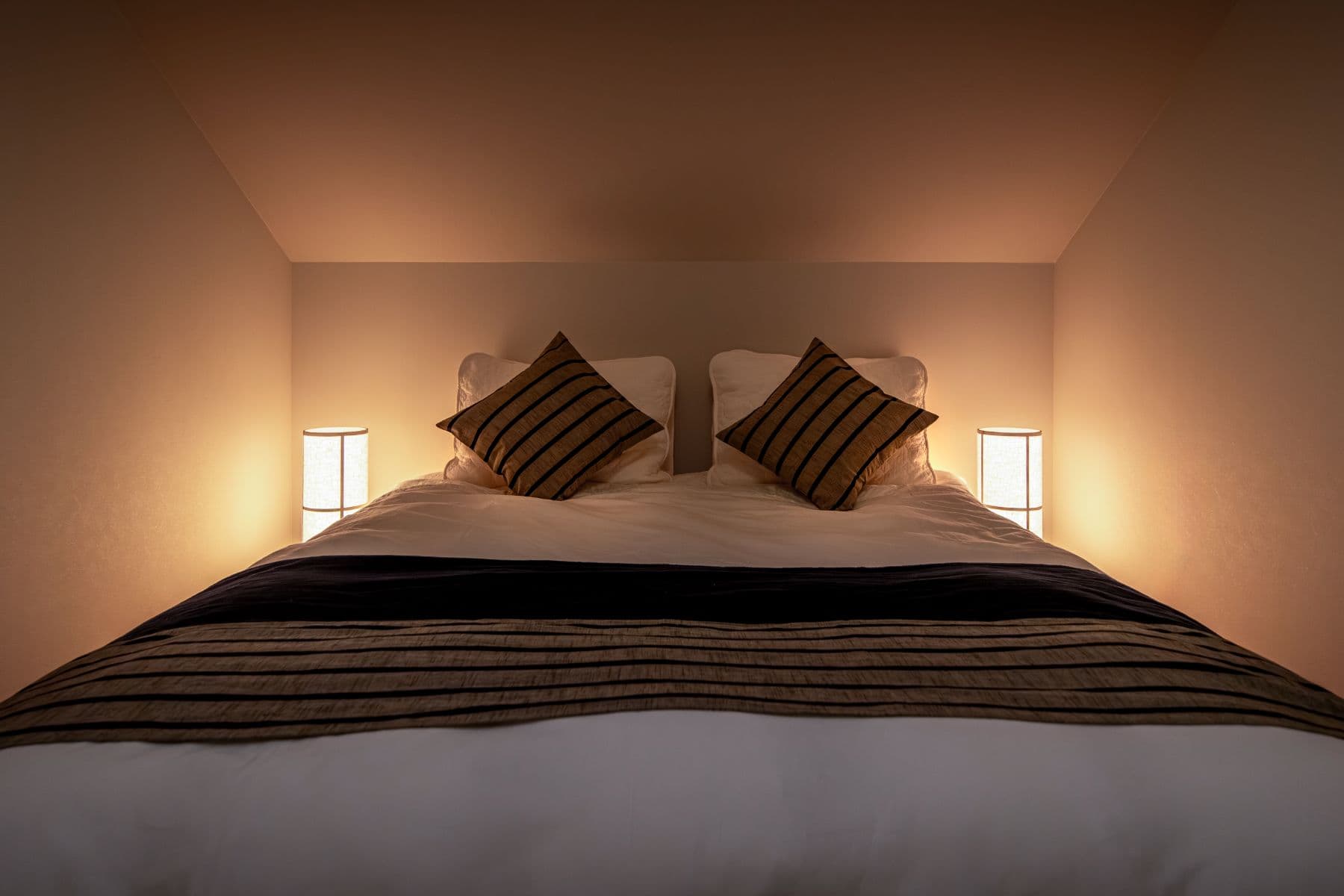 A queen-bed room lit by warm bedside lamps.